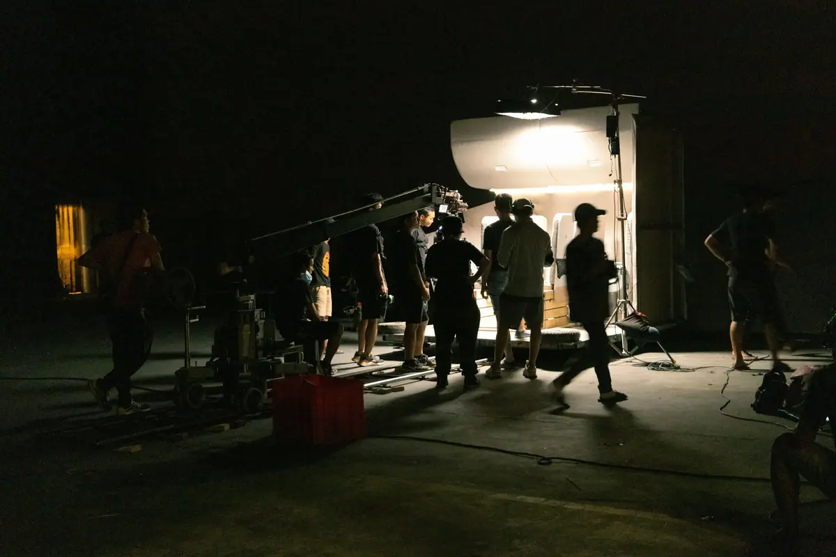 A film crew working under bright lights on a location shoot at night.
